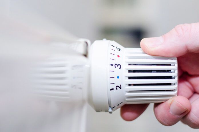 Close up of hand adjusting heating thermostat.